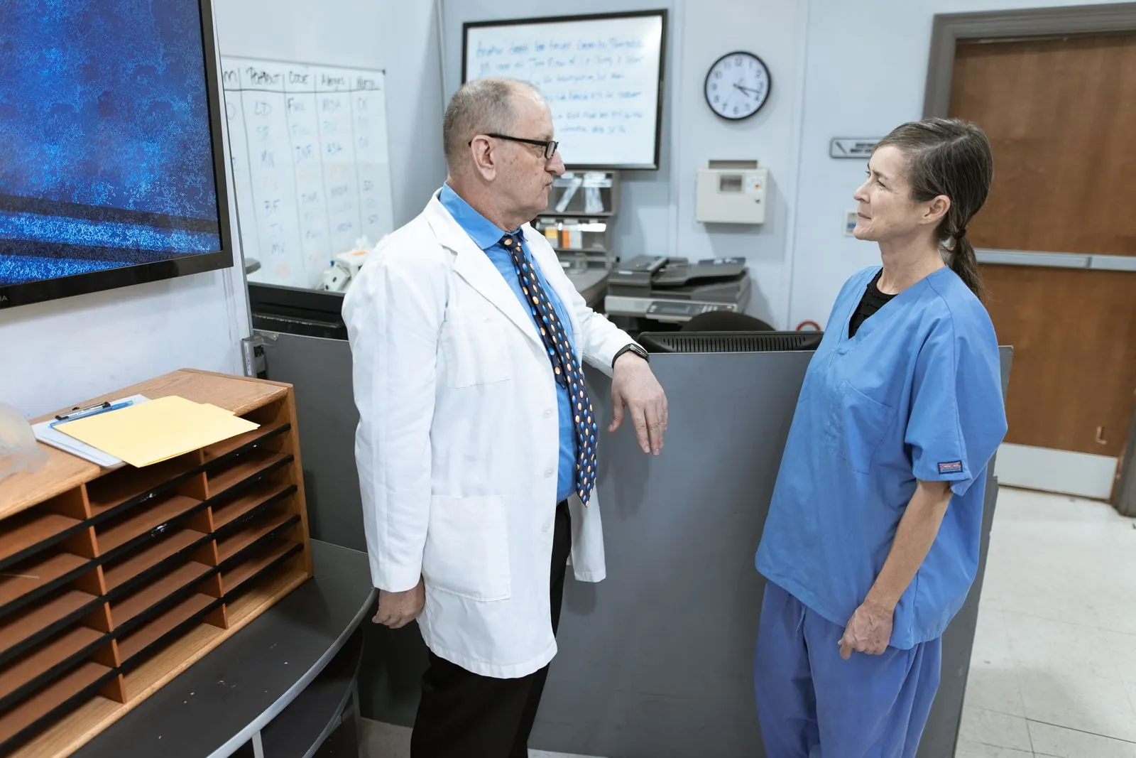Doctor and nurse discussing patient information in a hospital corridor